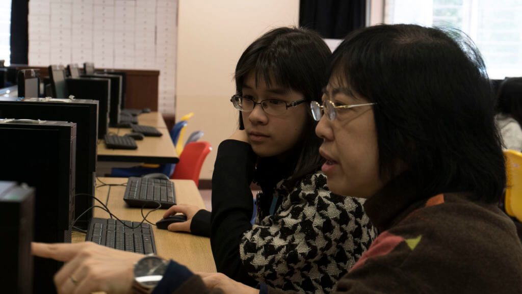 close up photo with a teacher teaching a student in computer room